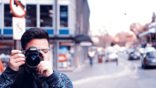 Man Holding A Camera On Busy Street photo