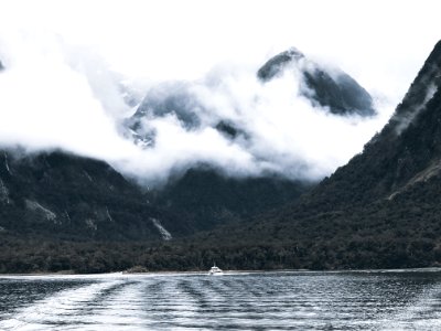 Photography Of Body Of Water Surrounded By Mountains And Fogs