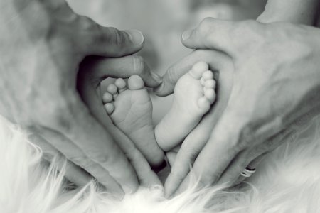 Grayscale Photo Of Baby Feet With Father And Mother Hands In Heart Signs