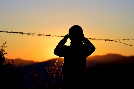 Silhouette Of Boy Standing Near Barbed Wire photo