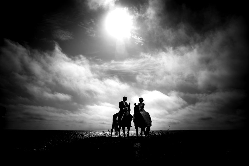 Grayscale Photography Of Couple Riding On Horse With Body Of Water And Sky As Background