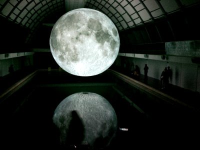 Photo Of Moon Hologram Floating On Water Near People Inside Room