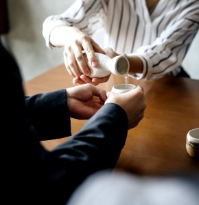 Person Pouring Liquid To Another Persons Cup