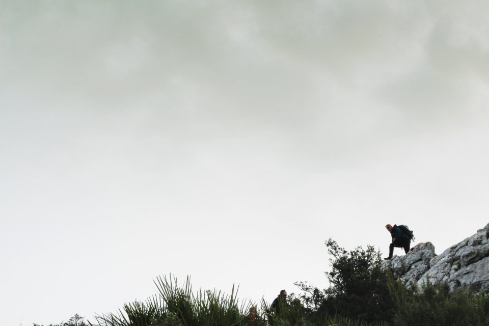 Person On Rocky Mountain Under White Cloudy Sky