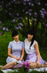 Two Women Wearing Purple Dress Sitting Side-by-side On Grass Field