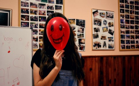 Woman Holding Red Balloon On Her Face Photo Inside Classroom photo