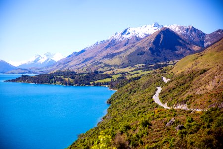 Grey Road Near Mountain Near Body Of Water Photo photo