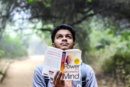 Man In Grey Shirt Holding Opened Book Looking Upward