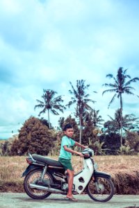 Boy Riding On White And Red Underbone Motorcycle photo