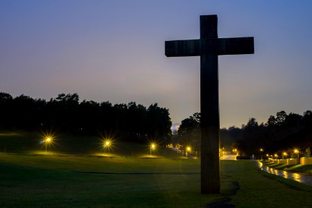 Brown Cross Statue On Green Grass Field With Turned On Light During Nighttime