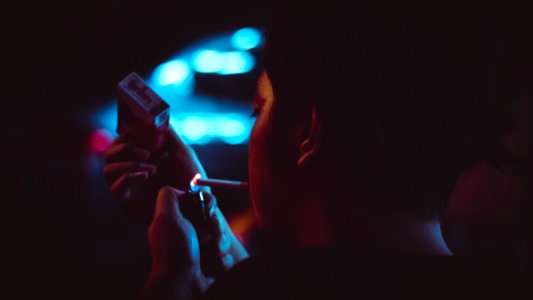Man Lighting Up A Cigarette During Nighttime In Tilt Shift Lens Photograhy