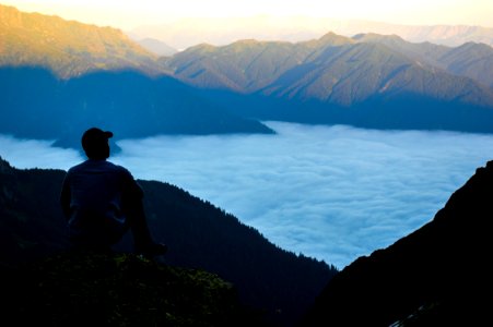 Man On The Edge Of The Cliff Above The Cloudy Sky