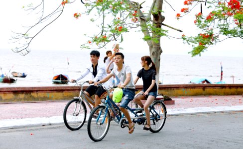 Two Boys And One Girl Riding Bicycles On Road Beside Body Of Water