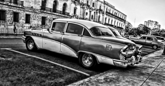 Greyscale Photo Of Vintage Car Parked Beside Building photo