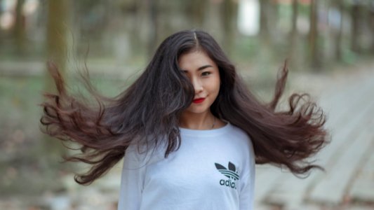 Woman With Long Hair Waving On Air And Wearing White Adidas Shirt photo