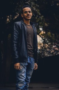 Man In Brown Shirt And Black Leather Zip-up Jacket And Blue Denim Pants photo