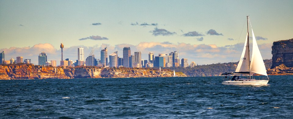 White Sail Boat Sailing On Body Of Water Near City Buildings photo