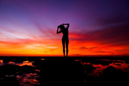 Silhouette Of Woman Standing On Rock photo