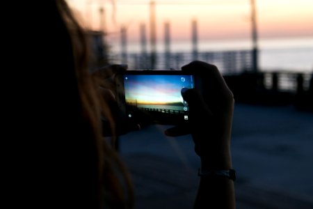 Brown Haired Woman Taking A Photo Of Sunset
