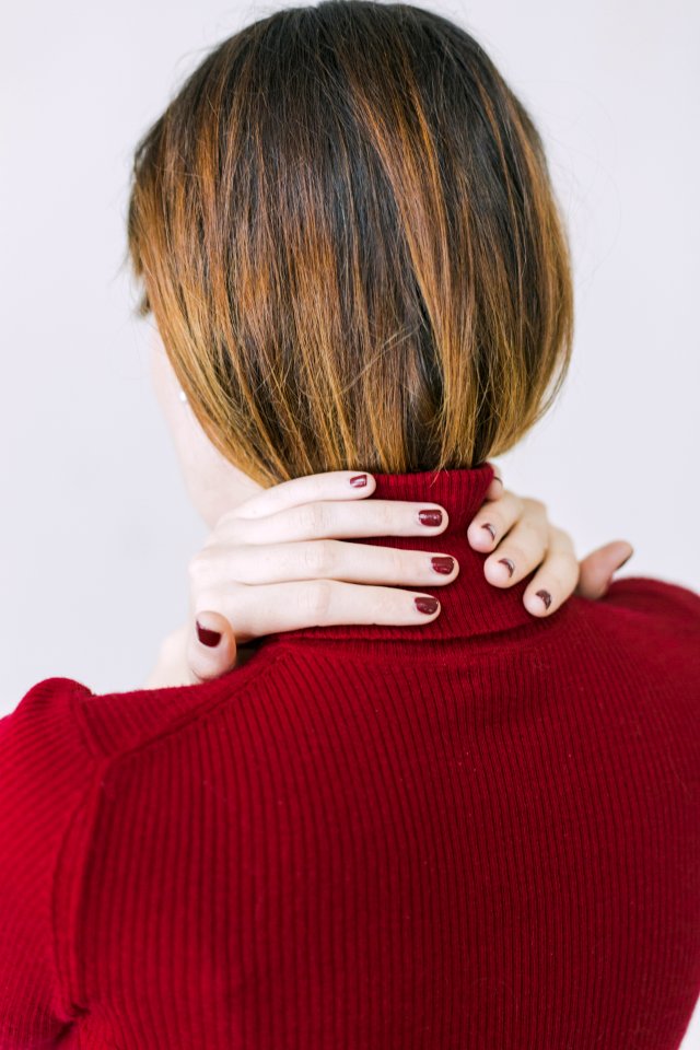 Woman In Red Turtle-neck Shirt Touching Her Neck