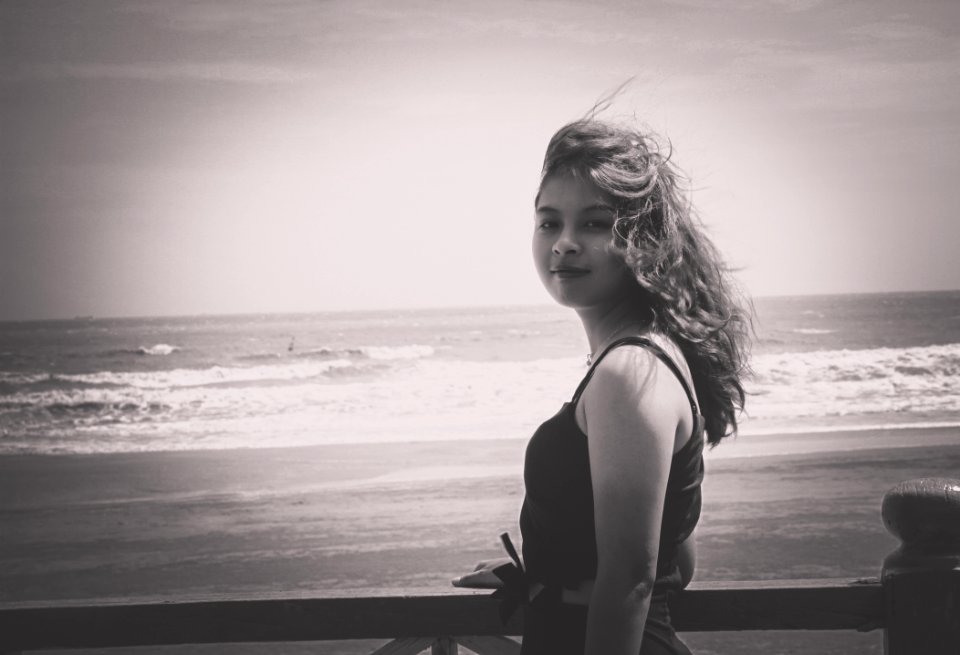 Grayscale Photo Of Woman Wearing Tank Top Standing Near Seashore