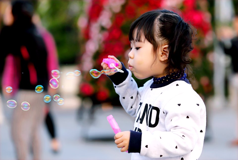 Toddler Girl Wearing White And Black Sweater Holding Plastic Bottle Of Bubbles At Daytime
