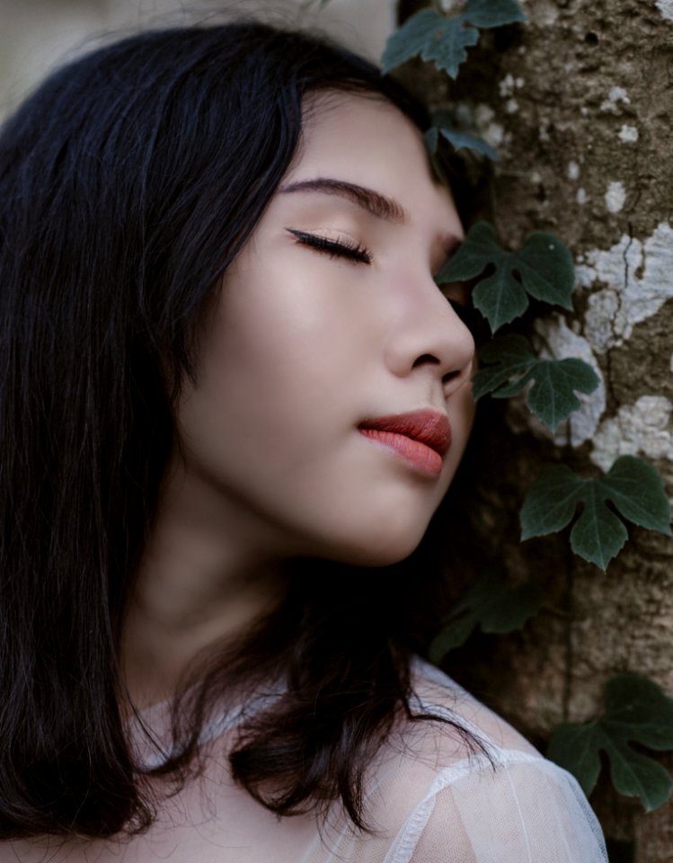 Woman Closing Her Eyes Beside Green Vine Plant