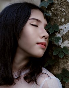 Woman Closing Her Eyes Beside Green Vine Plant