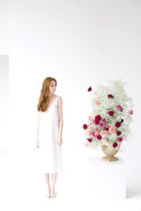Woman In White Spaghetti Strap Midi Dress Standing Beside Table With Flowers photo