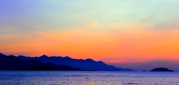 Silhouette Of Mountain Beside Ocean During Orange Sunset photo