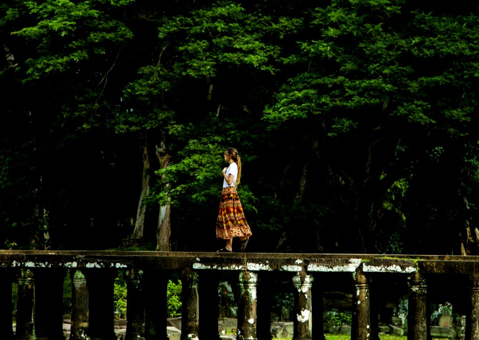 Woman Walking On Bridge Surrounded By Trees