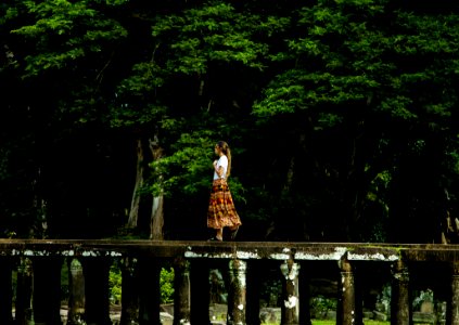 Woman Walking On Bridge Surrounded By Trees