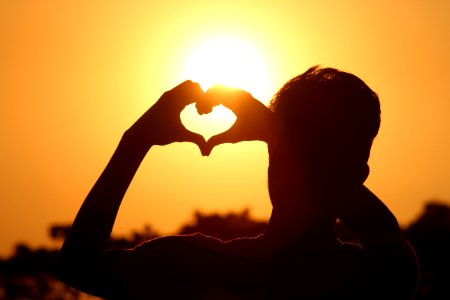 Silhouette Photo Of Man Doing Heart Sign During Golden Hour photo
