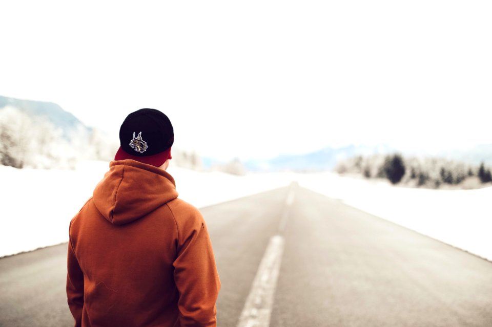 Person In Brown Hoodie Standing On Asphalt Road