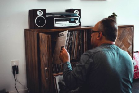 Man In Gray Longsleeve Shirt Holding Book In Front Of Brown Wooden Book Case photo