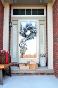 Four Brown Gift Boxes Near A Glass Paneled Door With Wreath