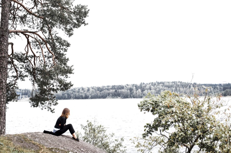 Woman Sitting On Gray Soil Near Body Of Water
