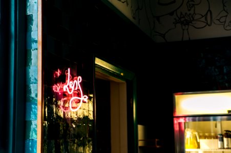 Less Neon Sign Mounted On Glass Board Near Open Window And Glass Display Rack