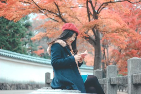 Woman In Blue Parka Jacket Sitting On Grey Concrete Bench Reading Book photo