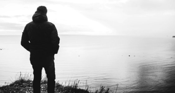 Silhouette Of Man Standing Near Body Of Water photo