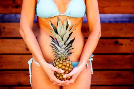 Woman Wearing Teal Bikini Holding Pineapple Fruit photo