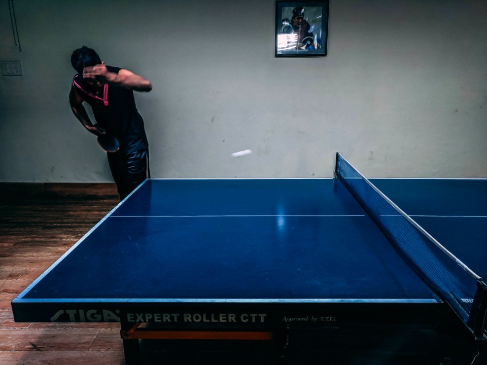 Man In Black Shirt Standing Near Blue Wooden Pingpong Table