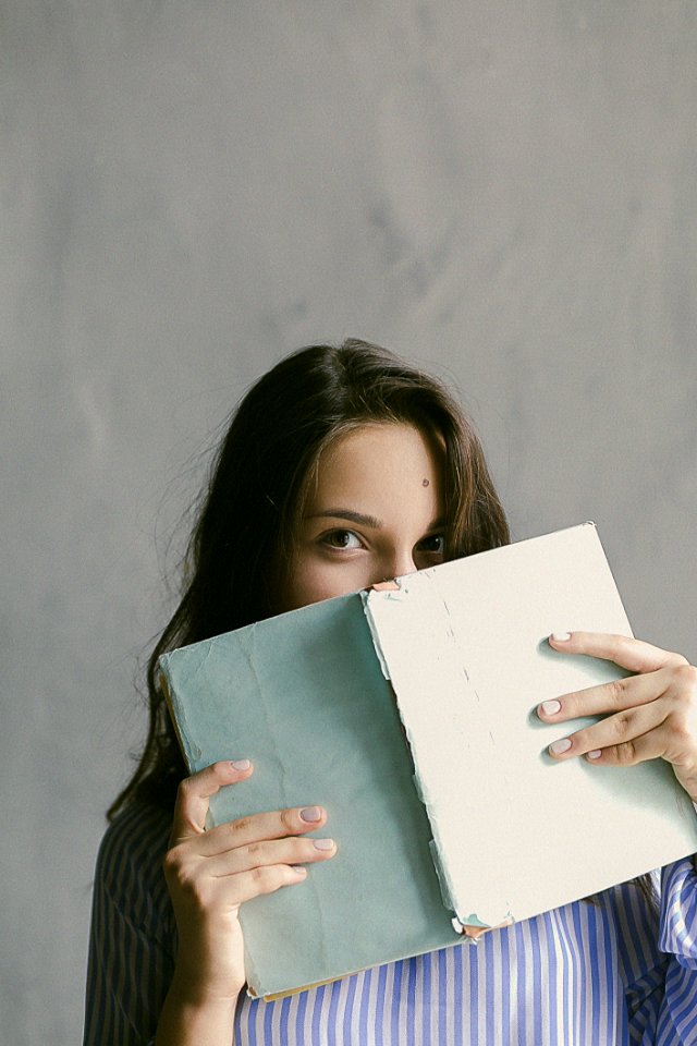 Woman In Blue Striped Flannel Shirt Holding A Book Indoors