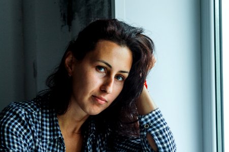 Woman In Black And White Gingham Long-sleeved Top Holding Her Hair Beside White Surface