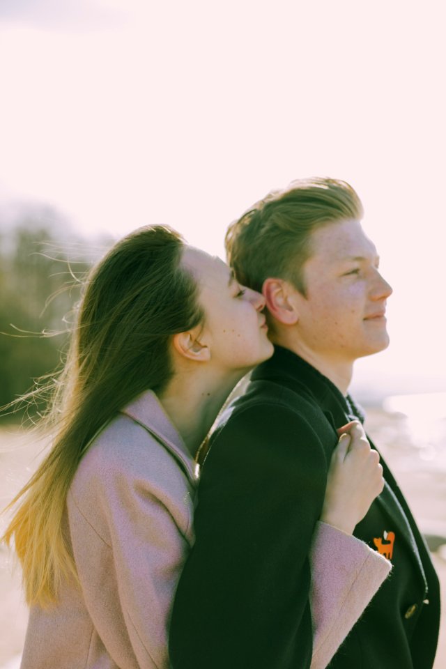 Woman Kissing The Back Of Mans Ear Near Sea