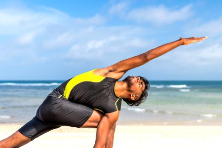 Man In Yellow And Black Tank Top Doing Exercise On Seashore At Daytime