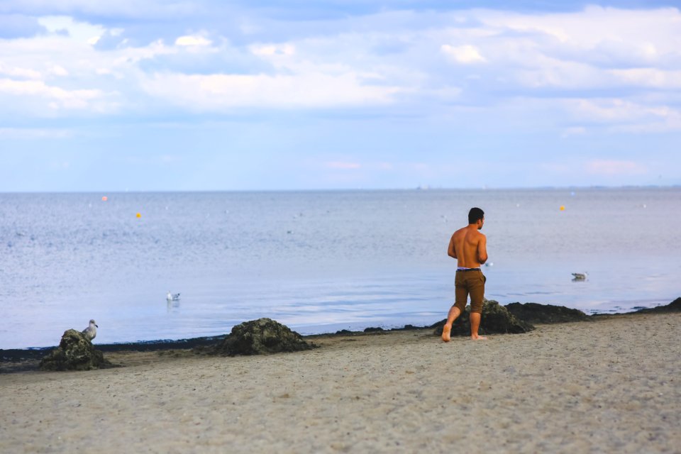 Young Man Walking On Sand Beach