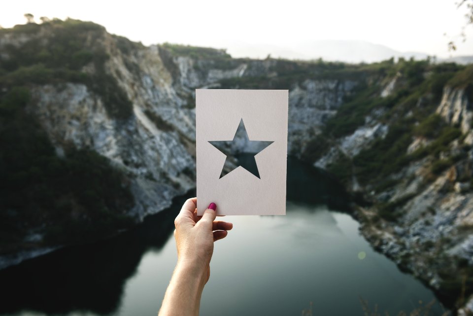 Person Holding Star Cutout Paper Facing Mountain