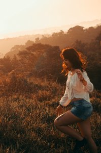 Women Wearing White Long-sleeved Blouse With Blue Denim Short Shorts Taken During Sunset