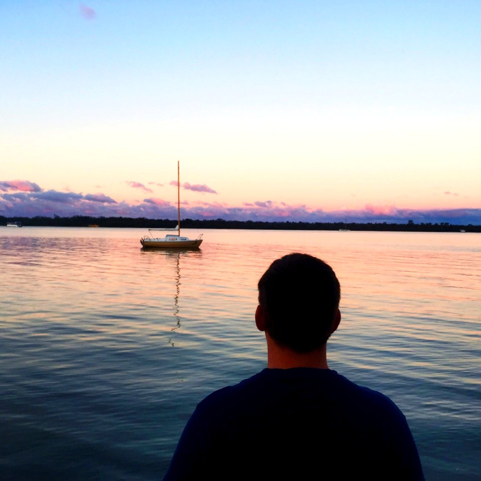 Man In Blue Shirt Near Blue Sea And White Boat Under Blue Sky